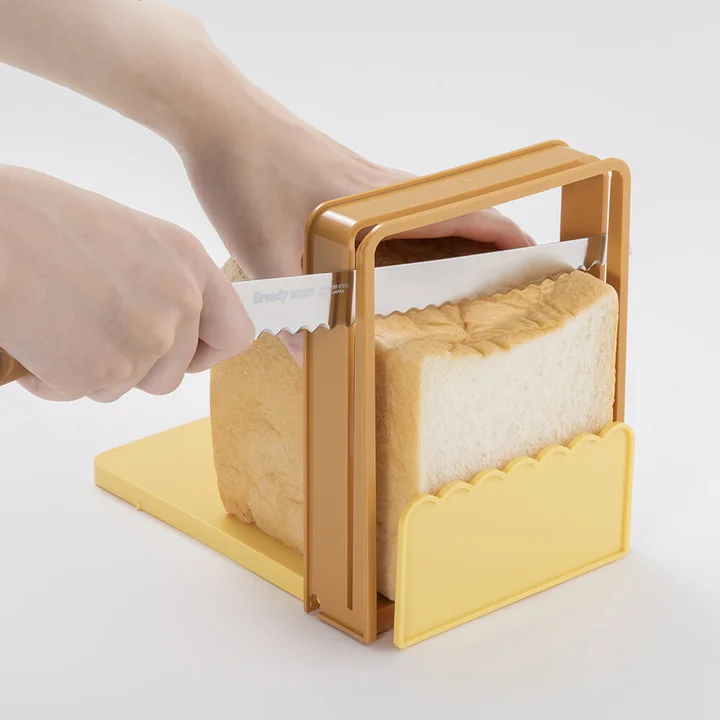 パン切りガイドに食パン一斤をはめてナイフを溝に通して切っているところ