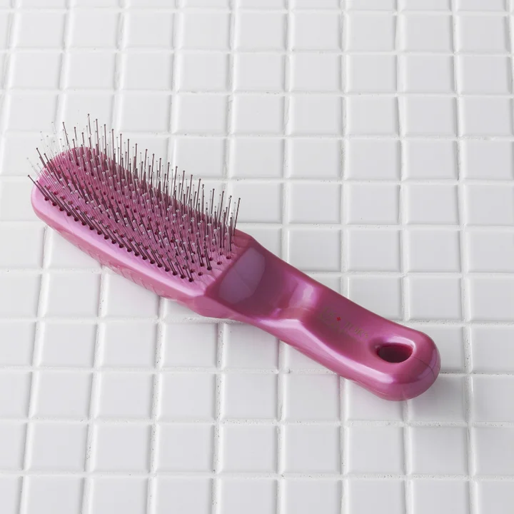 貝印 DOCTOR'S SCALP ドクターズスカルプヘアケアブラシ ピンクの本体 白いタイルの上に置かれた細いナイロンピンのブラシ