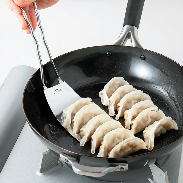 SELECT100 ターナーでフライパンに並んだ焼き餃子をすくっているところ