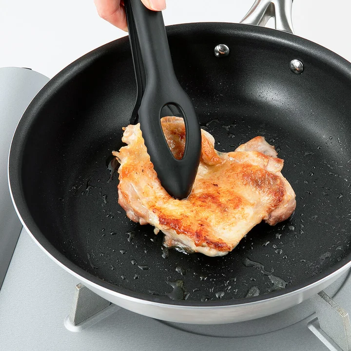 SELECT100 シリコーントング 24cmでフライパンの鶏肉をつかんでいるところ