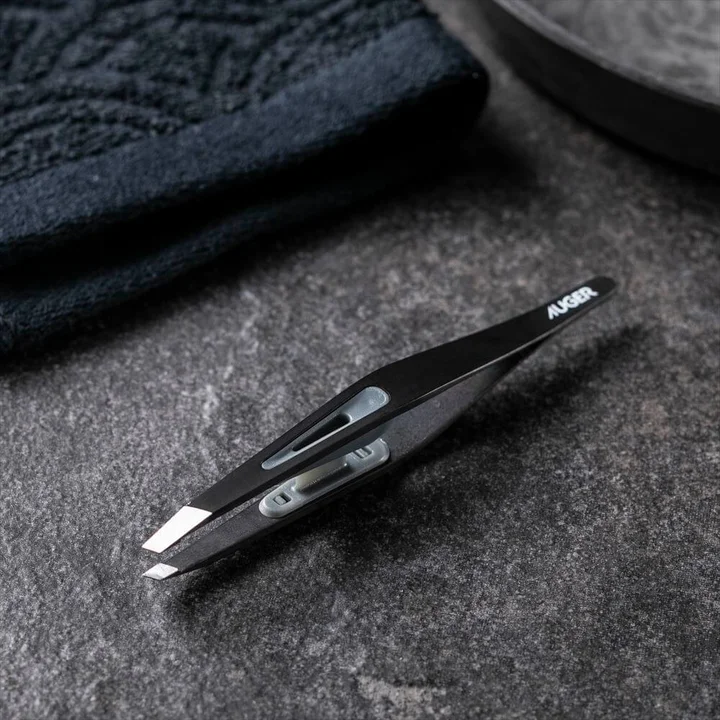 AUGER 毛抜きの全体。黒いチタンメッキの本体に AUGER のロゴ、中央にグレーのキャップ