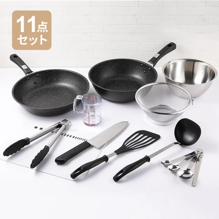 貝印の料理道具11点セット。フライパン・炒め鍋・ステンレスボール・ざる・計量カップ・トング・三徳包丁・フライ返し・おたま・計量スプーン・まな板が並んでいる