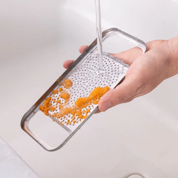 おろし器を水道の水で流して、にんじんの繊維を落としているところ