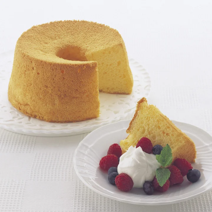貝印 アルミシフォン型で焼いたシフォンケーキ。白い皿の上に丸いケーキが置かれ、手前に切り分けた一切れとベリーが添えられている