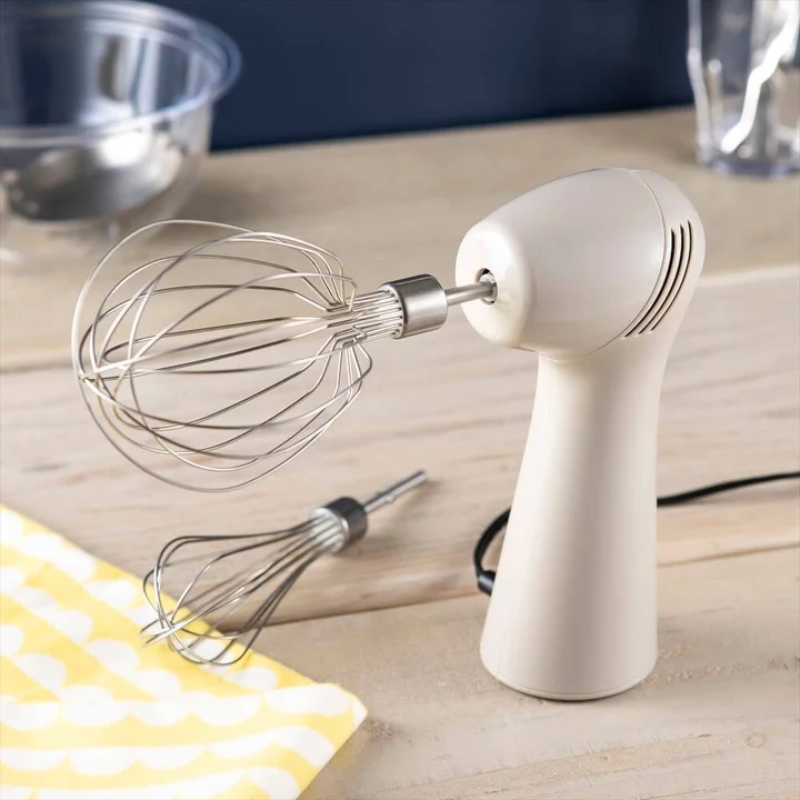 貝印 SMART WHIPPER GRAY の全体。ベージュがかったグレーの縦長の本体に、丸く膨らんだ大きなステンレスのウィスクが付き、手前に小さいウィスクが置かれている