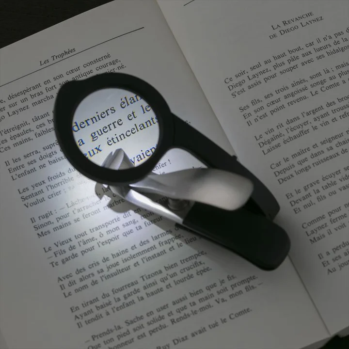 Kershaw ユニバーサルツメキリ LEDルーペ付きを本の上に置き、ルーペ越しに文字が大きく見えている