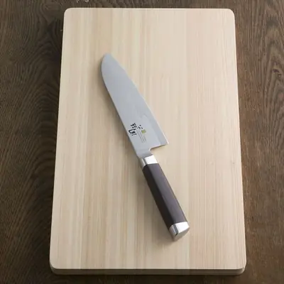 関孫六 15000ST 三徳包丁 165mm の全体。ひのきのまな板の上に置かれ、柄は濃い茶色の積層強化木で銀色の口金と尻金が付いている
