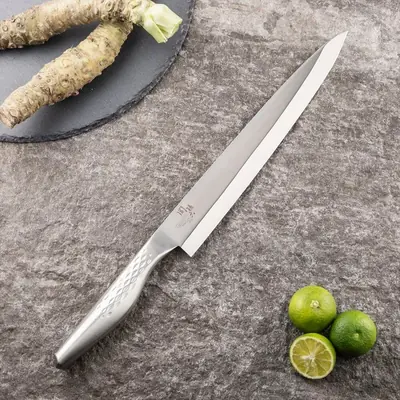 関孫六 匠創 刺身 240mm の全体。柄まで金属のオールステンレスで、横に生わさびと緑色の柑橘が置かれている